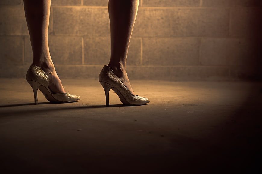 Woman's legs in gold glitter high heels on concrete floor