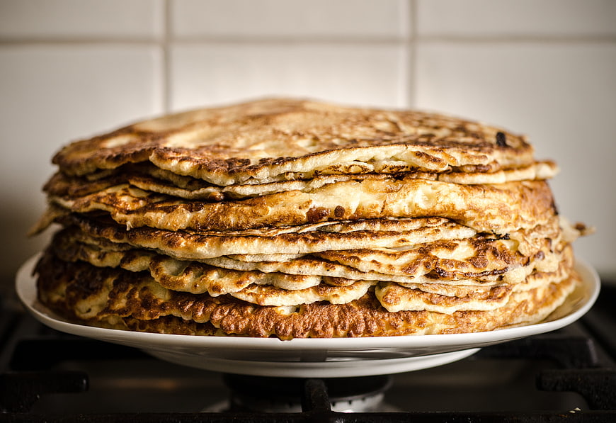 Stack of Golden Brown Pancakes on White Plate in Kitchen
