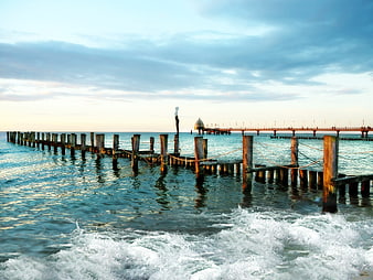 Woman standing on wooden pier in Baltic Sea at sunset