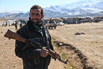 Afghan Man Holding Rifle In Rural Landscape