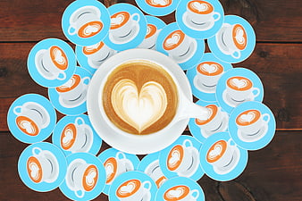 Flat lay of coffee cup with heart latte art surrounded by stickers