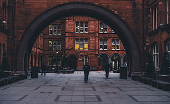 Red brick archway framing urban courtyard with people