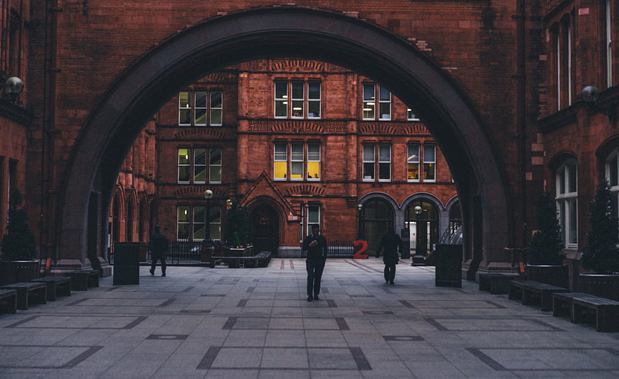 Red brick archway framing urban courtyard with people