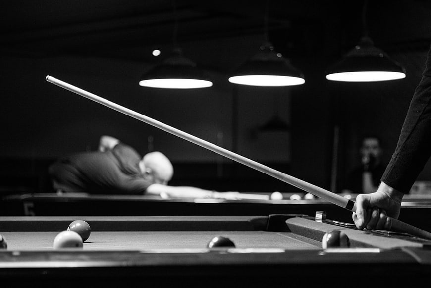 Black and White Pool Hall with Cue Stick in Foreground