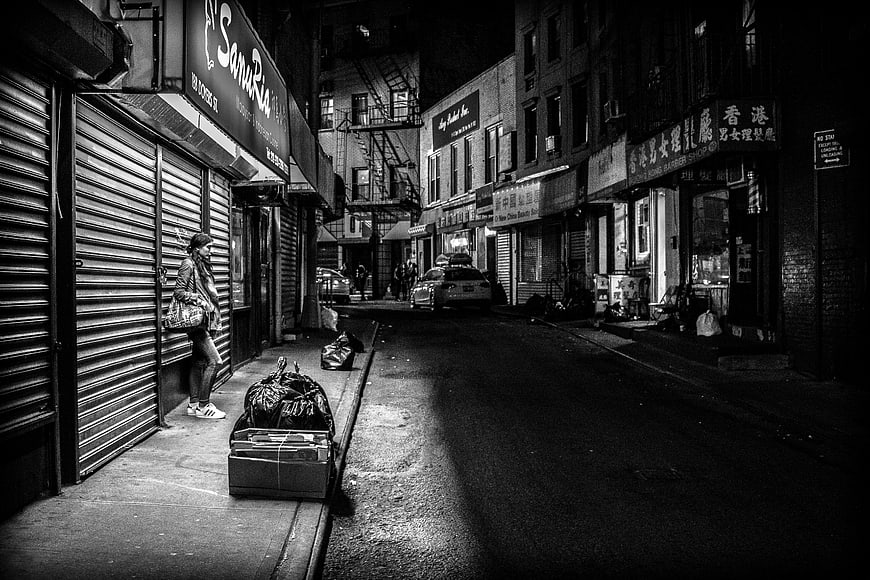 Woman waiting on dark urban street at night