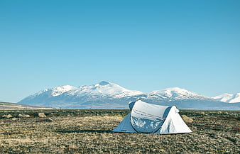 White tent camping in Icelandic landscape with snow-capped mountains