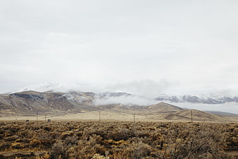 Snow-capped mountains with low clouds over arid sagebrush landscape