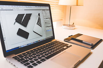 MacBook with graphics tablet and stylus on white desk