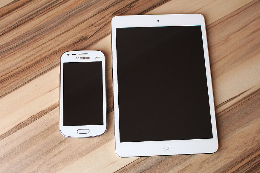 White smartphone and tablet on wooden surface