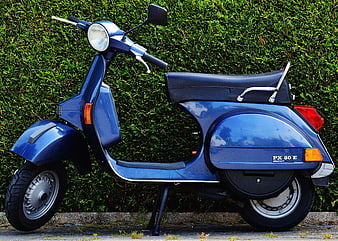 Blue Piaggio PX 80 E Scooter Parked by Green Hedge