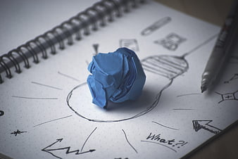 Blue crumpled paper ball on brainstorming sketch notebook