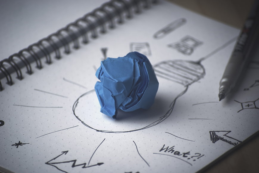 Blue crumpled paper ball on brainstorming sketch notebook