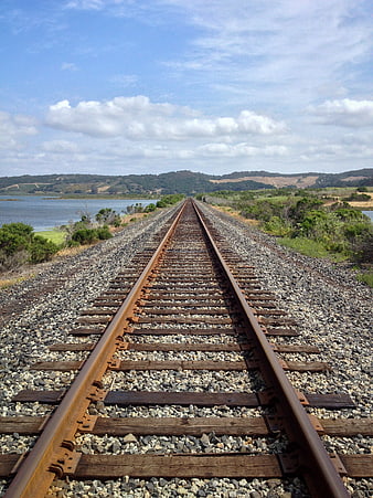 Railway Tracks Leading to Horizon Over Water and Hills