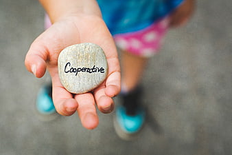 Child holding stone with word cooperative written on it