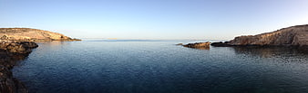 Panoramic view of calm blue sea between rocky cliffs