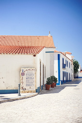 Sunny cobblestone street in Portuguese village with white buildings