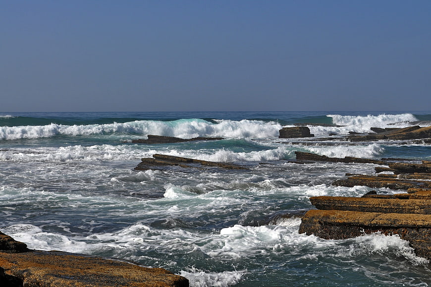 Rough ocean waves crashing on rocky coastal shelves