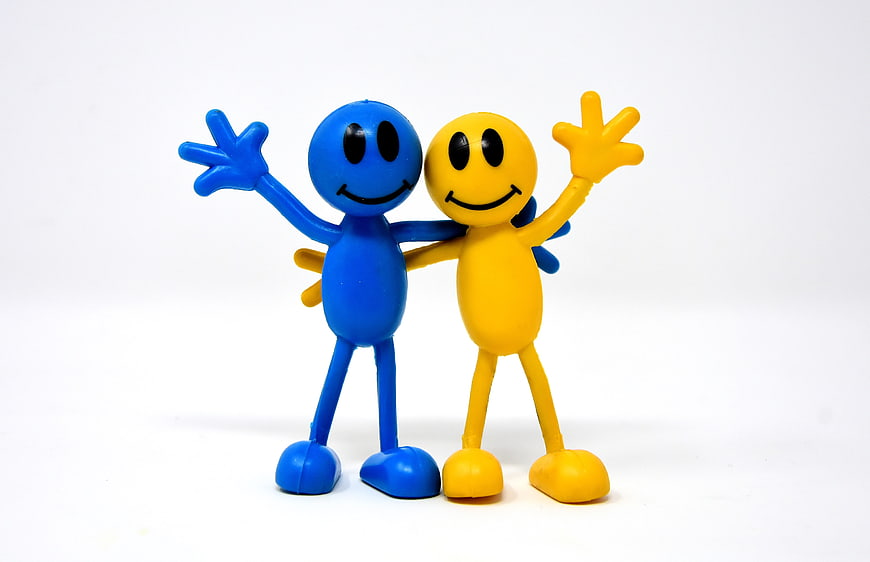 Blue and yellow smiley figures hugging on white background