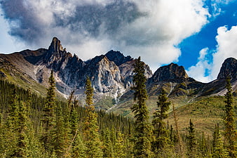 Rocky Mountain Peaks With Pine Forest And Dramatic Cloudy Sky