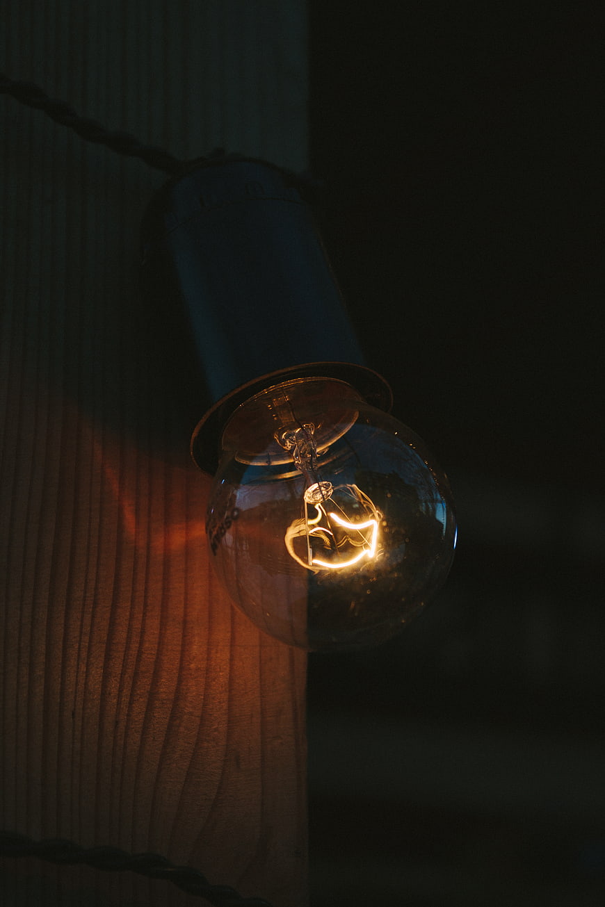 Vintage Edison Bulb Glowing Against Dark Wood Texture