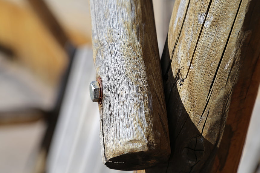 Close-up of weathered wooden beams with metal bolt
