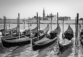 Black and white gondolas docked in Venice with church background