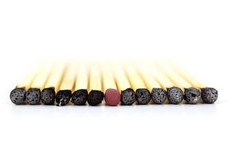 Red matchstick standing out among burnt black matches