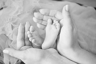 Black and white newborn baby feet held in mother's hands