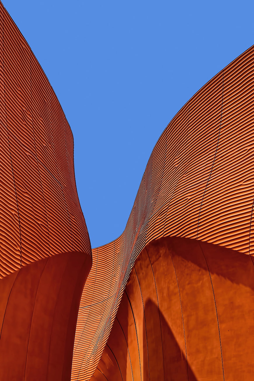Abstract Curved Orange Architecture Against Blue Sky