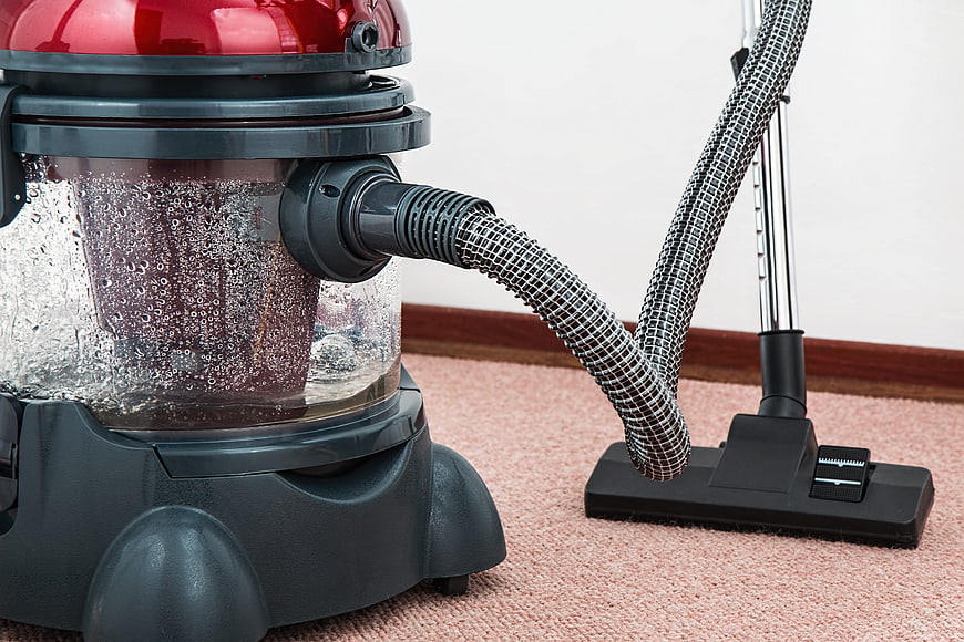 Red and black wet dry vacuum cleaner on pink carpet