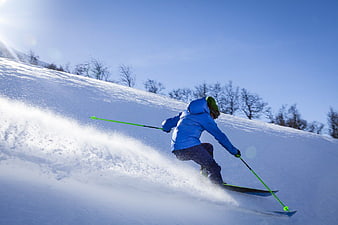 Skier in Blue Jacket Carving Down Snowy Slope