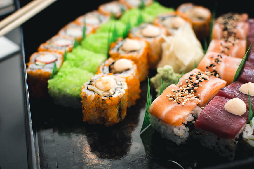 Assorted sushi platter with salmon, tuna, and rolls on black tray