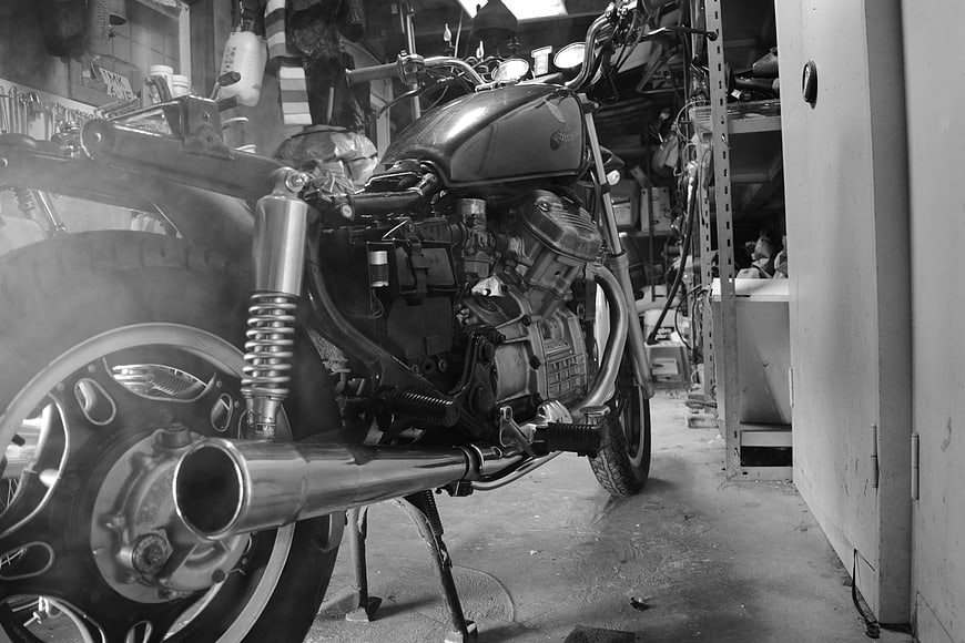 Black and white motorcycle engine in cluttered garage workshop