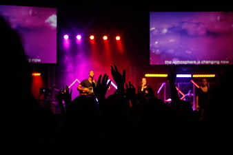 Silhouette of concert audience with raised hands on stage