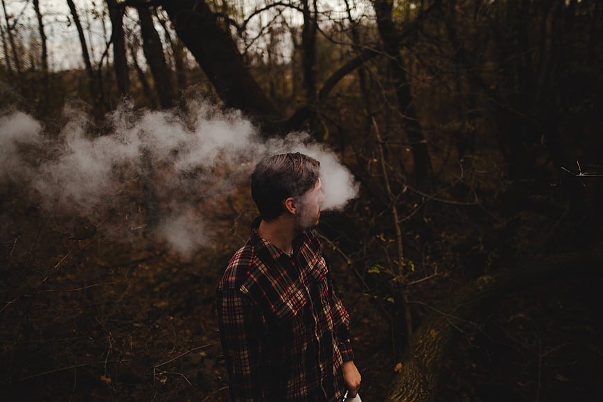 Man Smoking in Dark Autumn Forest with Smoke