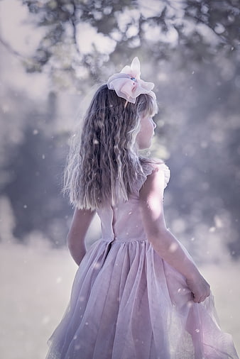 Young girl in pink dress with flower headband in dreamy outdoor setting