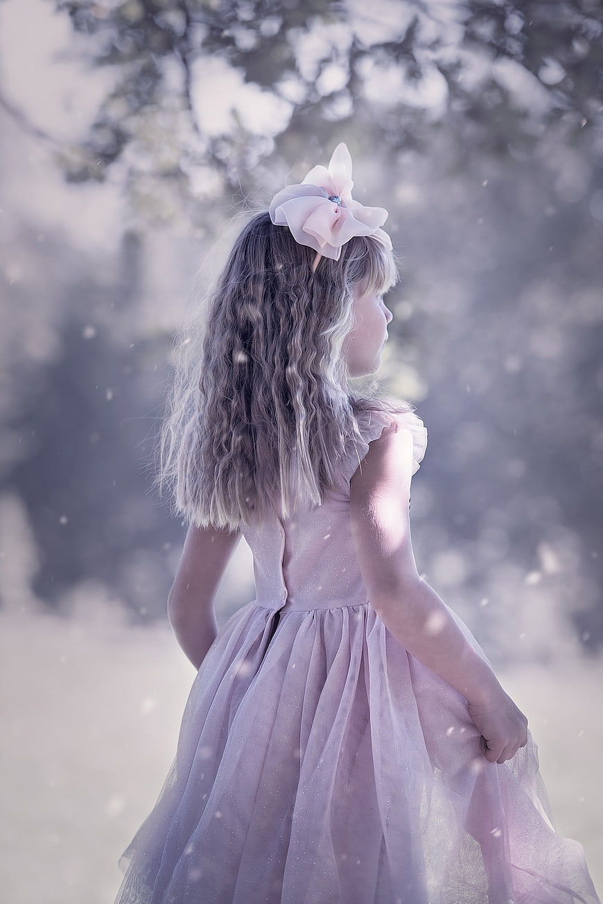 Young girl in pink dress with flower headband in dreamy outdoor setting