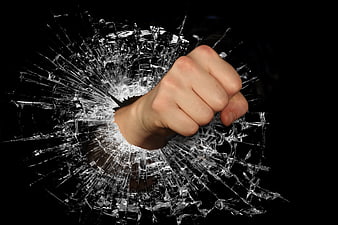 Fist Punching Through Shattered Glass on Black Background