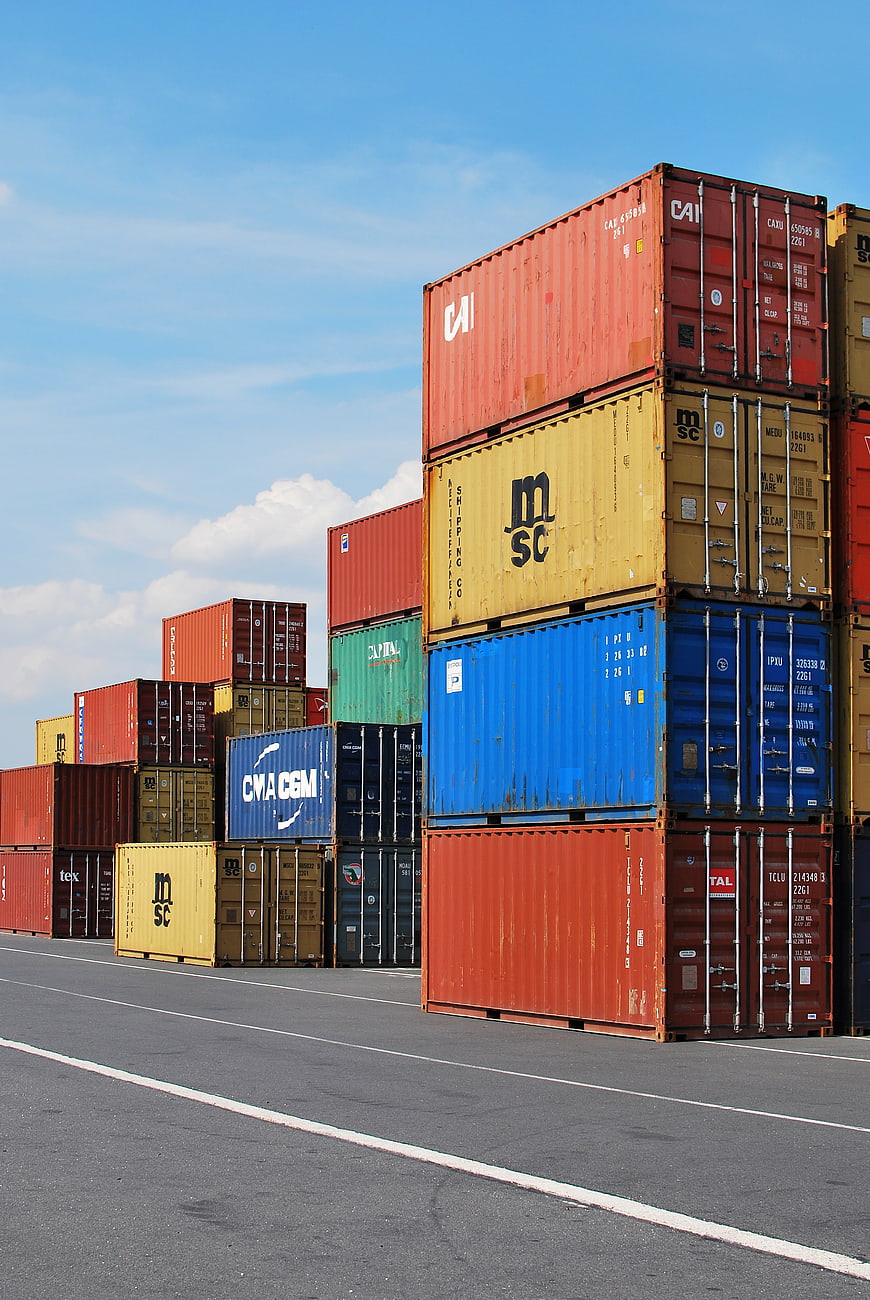 Stacked Shipping Containers at Port with Blue Sky