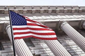 American Flag Waving in Front of Classical Building Columns