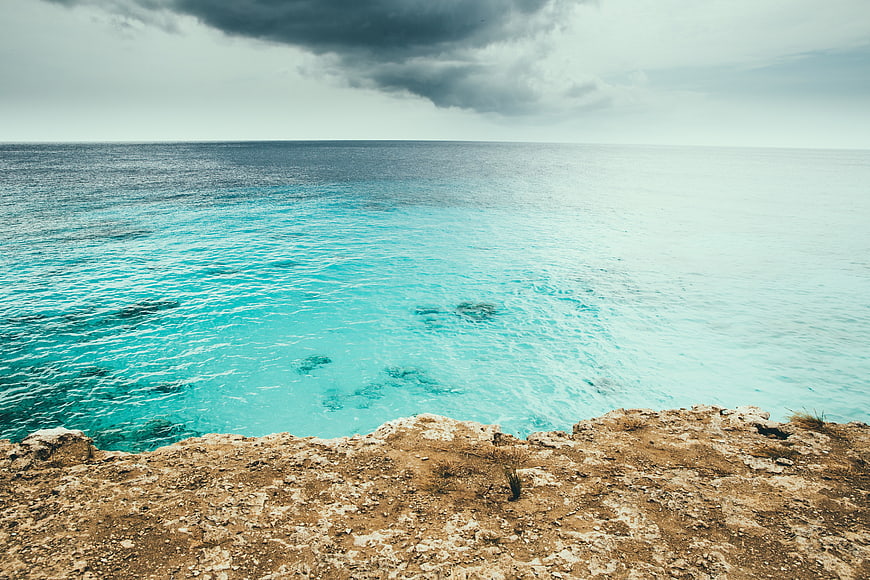 Dramatic turquoise ocean view from rocky cliff edge