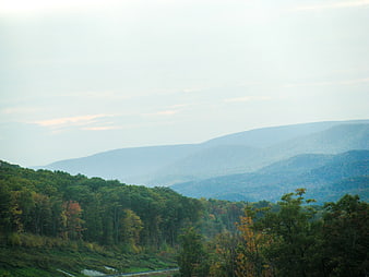 Misty Blue Mountain Range with Green Forest Hills