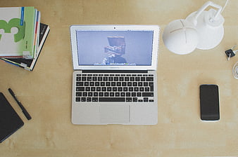 Top view of organized workspace with laptop, books, and lamp