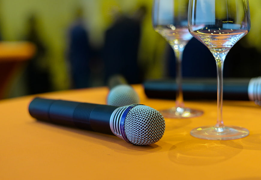 Close-up of wireless microphone and wine glasses on table
