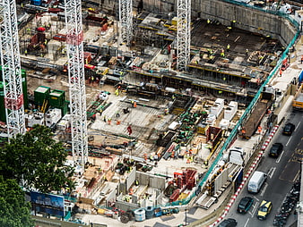 Aerial view of busy urban construction site with cranes and workers