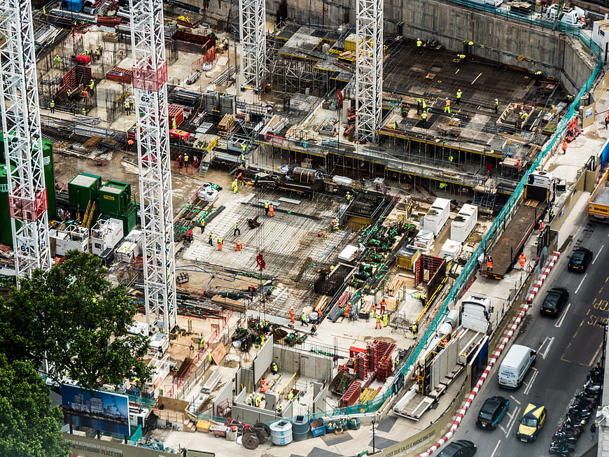 Aerial view of busy urban construction site with cranes and workers