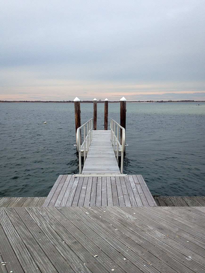 Wooden dock extending into calm water under overcast sky
