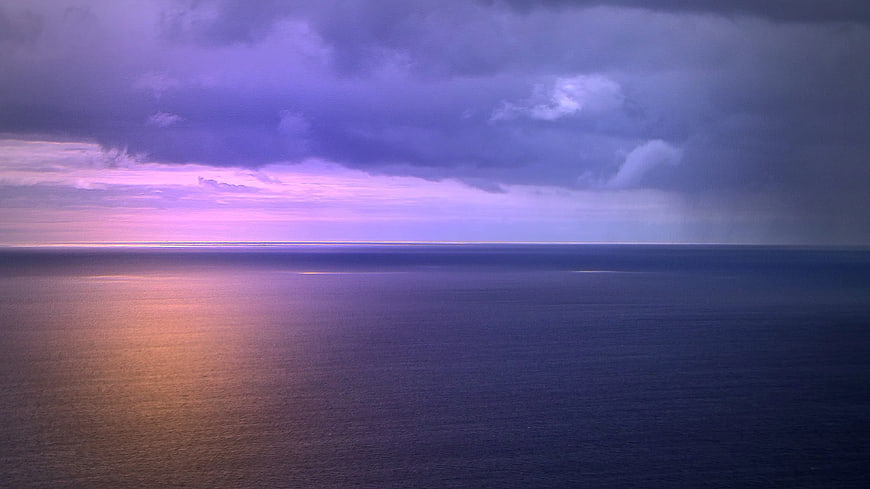 Dramatic purple sunset over calm ocean horizon