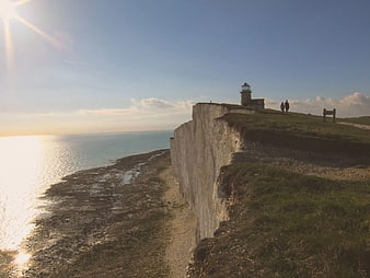 Lighthouse on White Cliffs Overlooking Ocean at Sunset