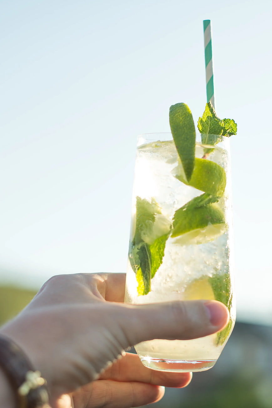 Hand Holding Refreshing Mojito Cocktail with Mint and Lime